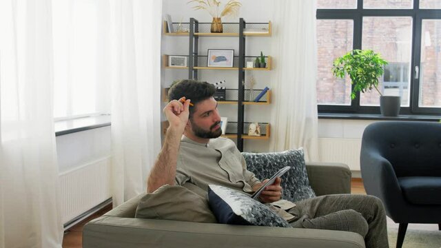 planning and people concept - man writing to notebook and thinking at home