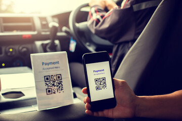 Blurry image of Hand using smart phone to scan QR code on tag with blurry car rental driver in car...