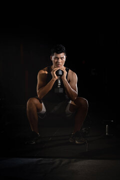 Handsome man holding dumbbell in hand and squash,doing exercise for built muscle,fit and firm body