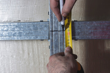 The employee measures the length of the profile using a tape measure. Close-up