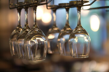 close up row of drinking glasses hanging upside down in bar. Bokeh background