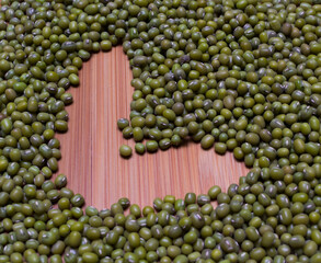 heart arranged by Green beans, wooden background isolated