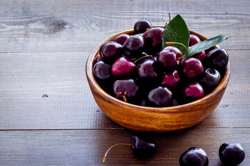 Red cherries with leaves in the bowl. Berries background