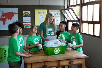 Female teacher and group of kids with recycle container in class at school