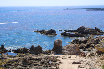 a gorgeous shot of the deep blue ocean water, the lush green hillside and the rock formations of...