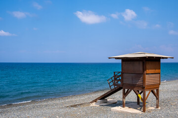 Fototapeta na wymiar Wooden lifeguard safety station against blue water and sky