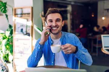 Smiling man speaking on phone in cafe