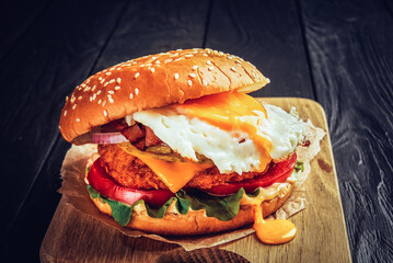 Beef burger with melted cheese and bacon and egg on wooden background