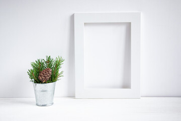 A bouquet of green spruce branches in an iron bucket and a white frame for text on a white background. Christmas composition.