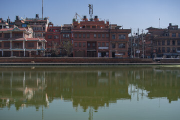 Bhaktapur, Kathmandu, Nepal - December 23, 2019: Reflection in a water pond of a stone wall and a few old residential buildings on December 23, 2019 in Bhaktapur, Kathmandu, Nepal