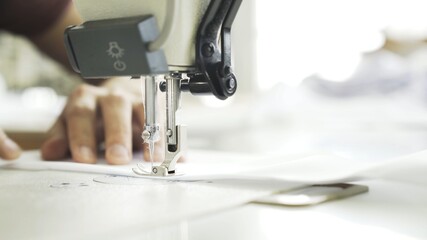 Hands and white cloth close up, sewing on machine. Digital machine, power button, female hands on white machine with blurry background
