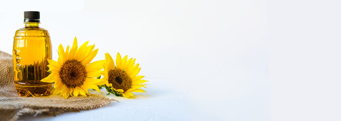 sunflower oil poured into bottle is on a canvas napkin. next to the flowers. on white background
