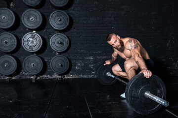 Young sweaty fit strong muscular man with big muscles checks heavy weight plates on the barbell and...