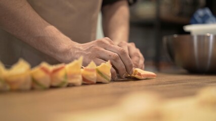 Male hands laying tortellini on wooden tray, on wooden kitchen table close up. Male hands cooking italian food, handmade tortellini at the restaurant kitchen