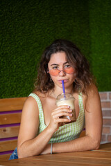 Young girl looking at camera while drinking a smoothie.