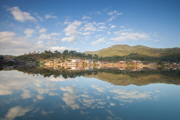 Fototapeta na wymiar village on mountain reflection on water againts sky