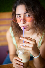 Young girl looking at camera while drinking a smoothie.