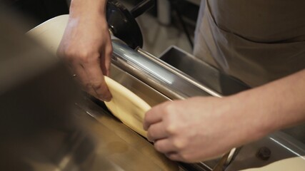 Male hands rolling dough, making italian food, process of ravioli making at the restaurant kitchen. Rolling dough for ravioli preparation, no face
