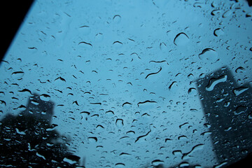 Rain drops on car windows with Towers in background. Urban life concept. Flood in cities.