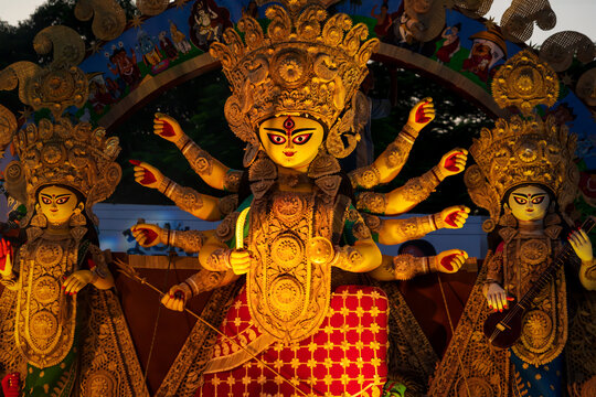 Happy Durga Puja Background. Goddess Durga idol at puja pandal, shot at colored light at Kolkata. Biggest traditional religious festival of Hinduism celebrated worldwide.