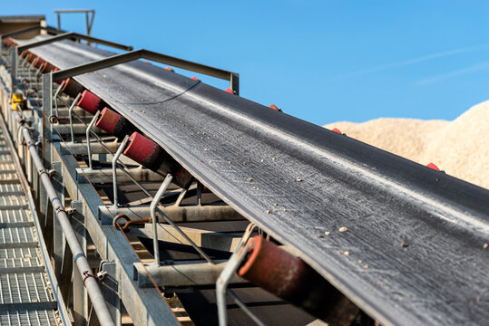 Close-up shot of the conveyor belt in the concrete plant with transport rollers, visible metal stairs.