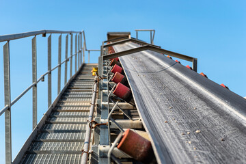 Naklejka premium Close-up shot of the conveyor belt in the concrete plant with transport rollers, visible metal stairs and railings.