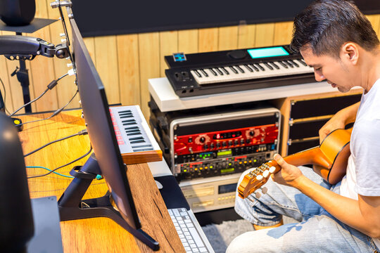 asian male musician, producer playing and recording guitar in music studio. music production concept
