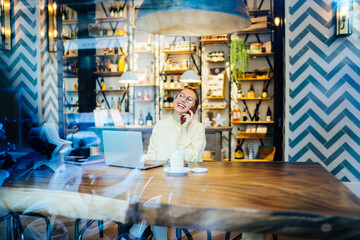 Happy woman talking on smartphone in cafe