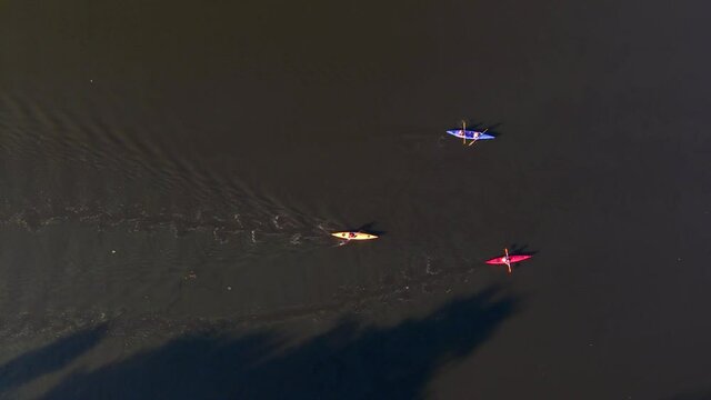 Aerial drone shot of people riding a multicolor cayaks on small river, bird eye view 4k footage