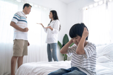 Fototapeta na wymiar Crying illtle asian boy with his fighting parents in the background, Family problems, Divorce problem.