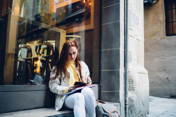 Fototapeta na wymiar Young woman reading near cafe