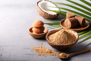 Different shape of organic brown palm sugar on grey concrete background with copyspace.