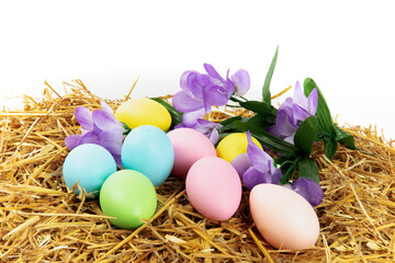 Fototapeta na wymiar Easter on the farm, colorful Easter eggs and flowers on a hay bale isolated on white