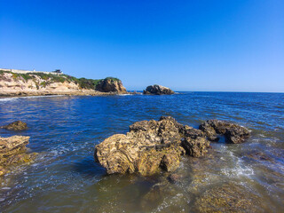 gorgeous aerial shot of the waves and the deep blue ocean water and the large rocks on the beach...