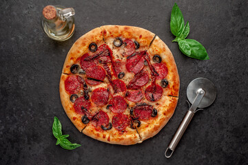 pizza pepperoni with salami sausages, mozzarella, olives, Provencal herbs, signature tomato sauce on a stone background