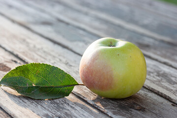 Yellow apple with green leaf on wooden table