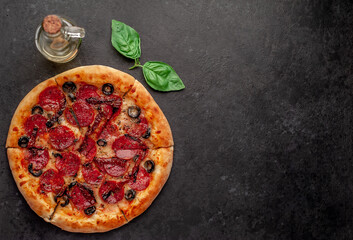 pizza pepperoni with salami sausages, mozzarella, olives, Provencal herbs, signature tomato sauce on a stone background 
with copy space for your text