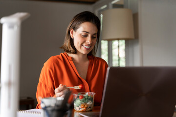 Smiling business person eating salad at home