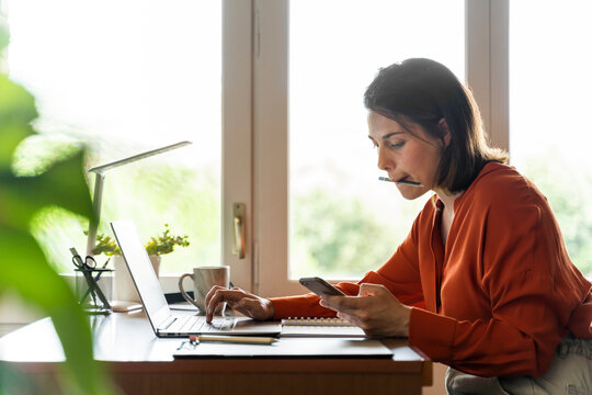 Businesswoman using mobile phone while working at home