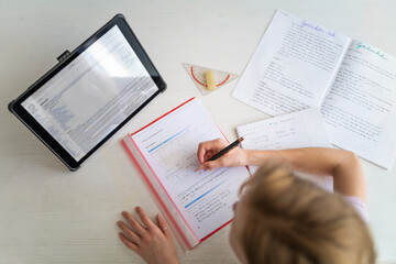 Blond girl learning and using tablet at home