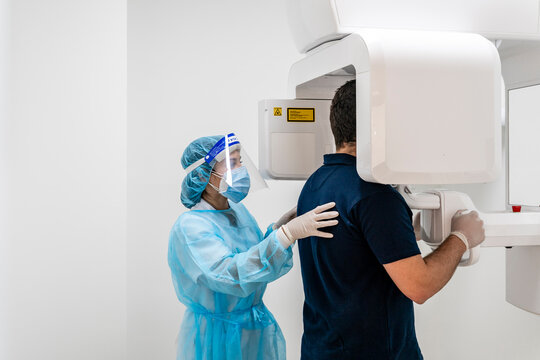 Female Nurse Helping Male Patient In Scanning At Hospital