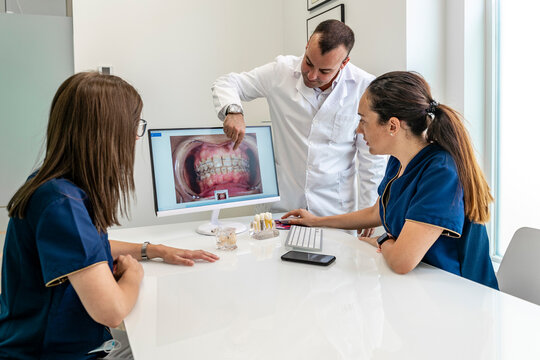 Dentist discussing with female doctors discussing while looking at x-ray in clinic