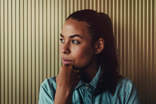 Close-up of thoughtful young woman looking away against wall