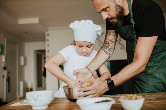 Father and daughter baking cookies at home