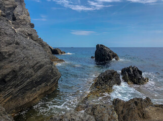 Fototapeta na wymiar rocks in the sea close-up across bly sky and horizon. Italian Liguria. Summer vacation. 