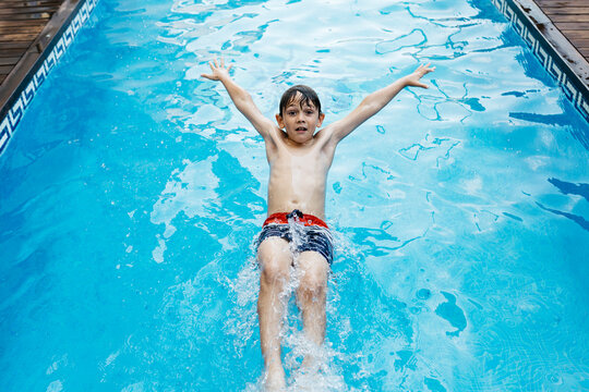 Boy doing backstroke jump in pool