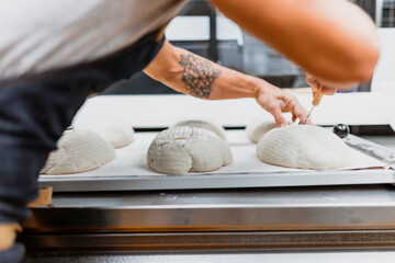 Baker carving shape on bread at bakery