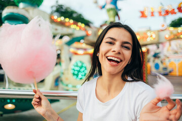 Close-up of beautiful woman holding cotton candy laughing in amusement park
