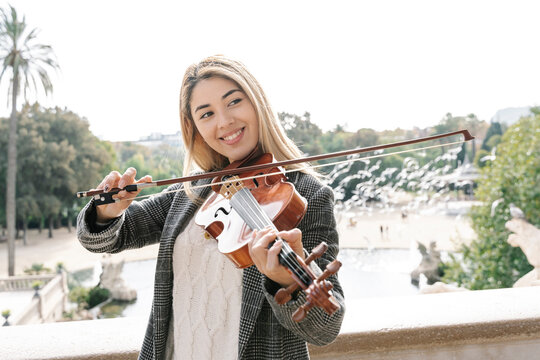 Blond young woman playing violin in city