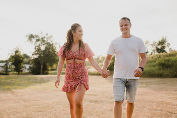Happy couple walking hand in hand on a meadow